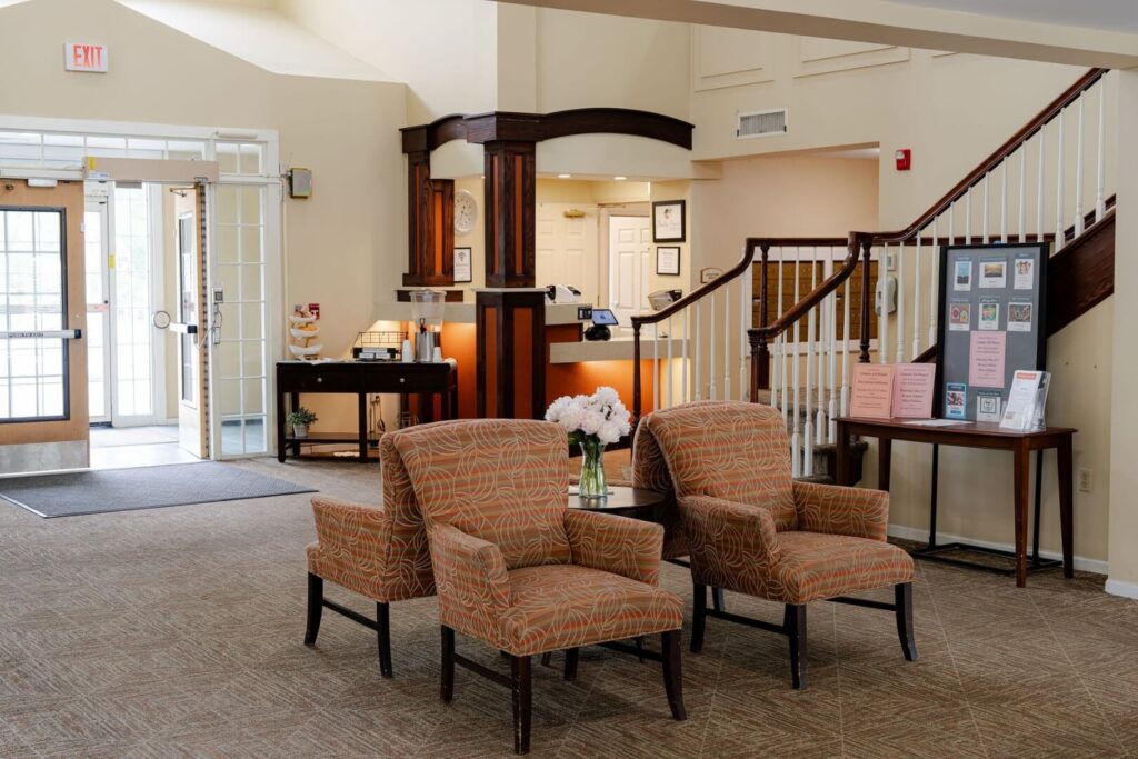 Welcoming Reception Lobby with Seating and Staircase at Assisted Living Community