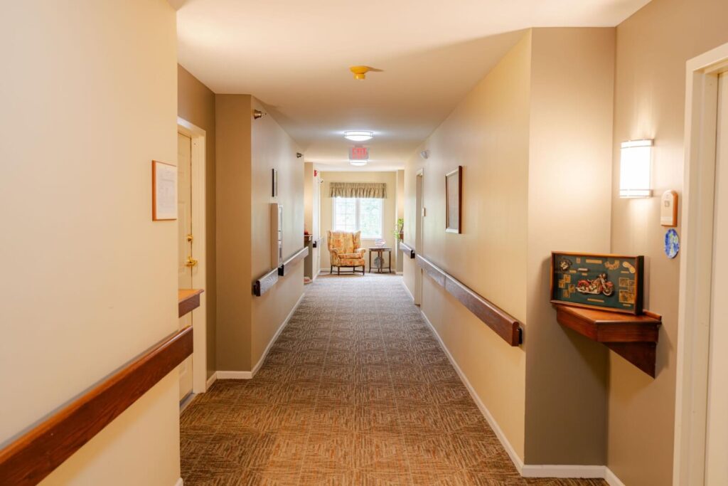 Carpeted Resident Hallway with Wooden Handrails in Assisted Living Community