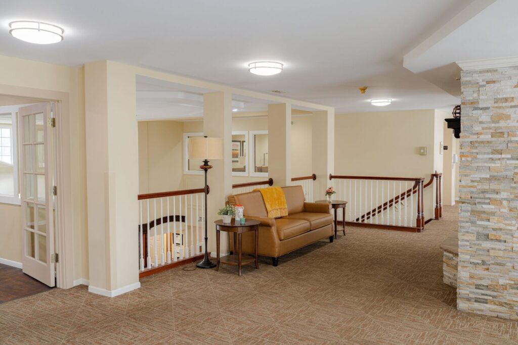 Upstairs Sitting Area with Leather Sofa and Staircase in Assisted Living Community