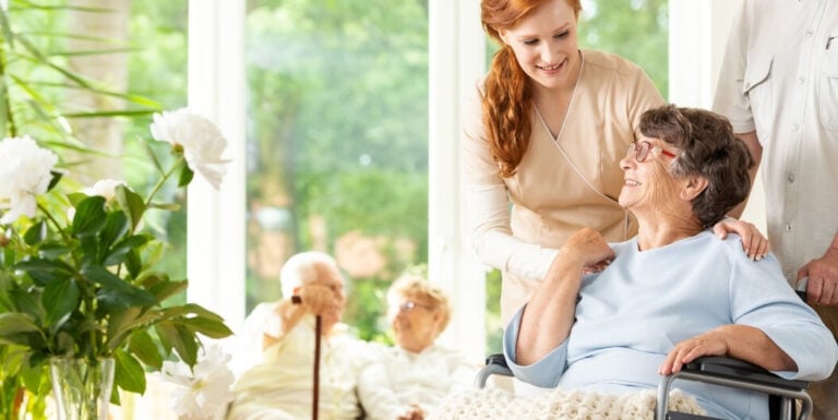 Female Nurse Assisting Resident in Wheelchair at Assisted Living Facility
